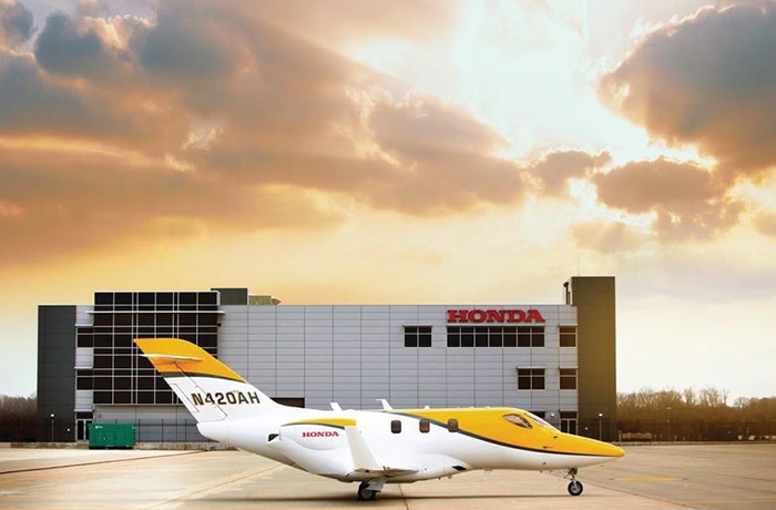Image of yellow Honda Jet in front of a Honda building. 
