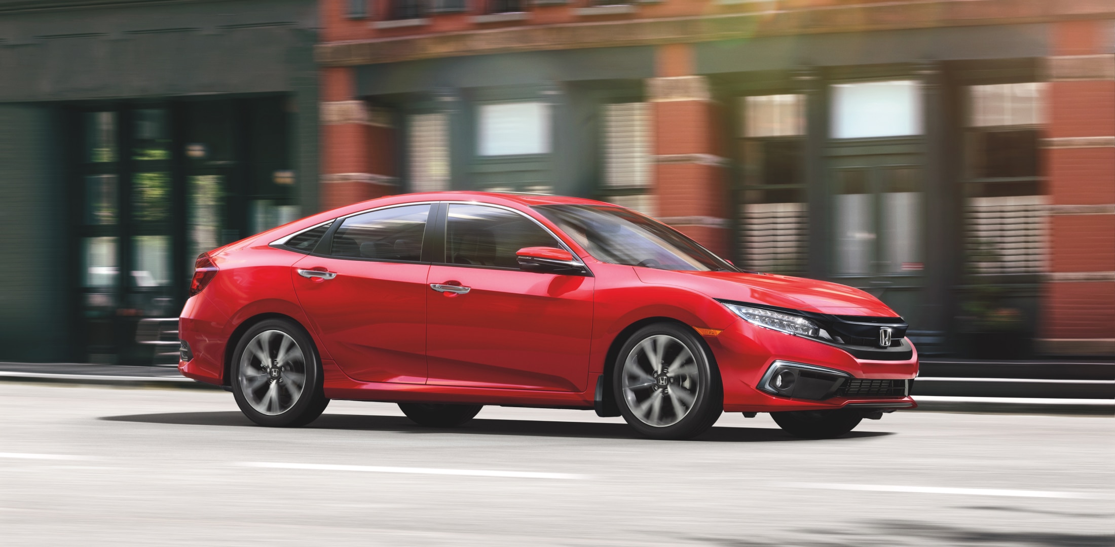 A red Honda Civic on a city street.